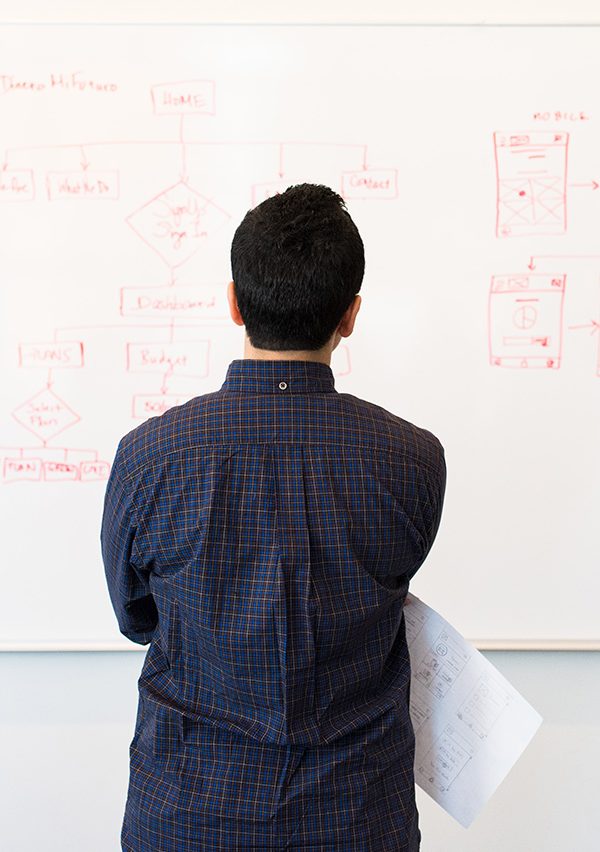 man studying diagrams on a white board