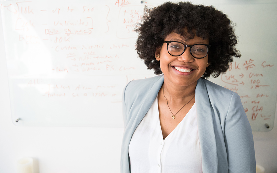 smiling woman standing in front of a white board