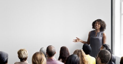 woman giving presentation to room full of people
