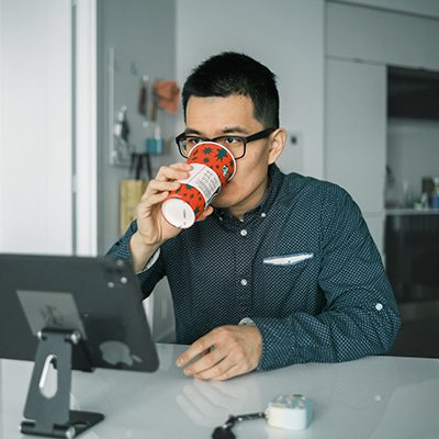 man sitting at computer drinking coffee
